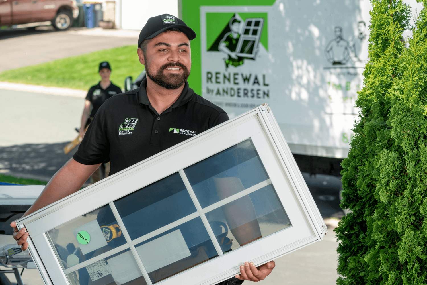 A Renewal by Andersen installer carrying a white window from a van into a homeowners house