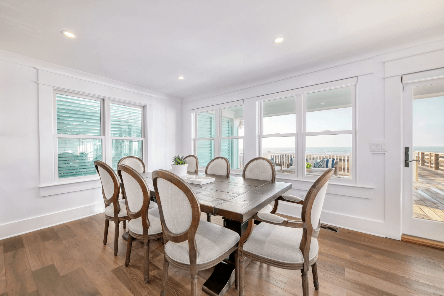 A dining room featuring hardwood floors and Renewal by Andersen's composite Windows, with a view of the ocean outside