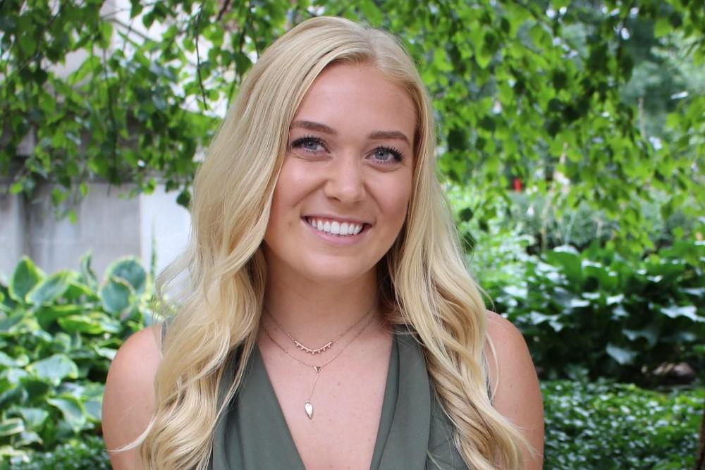 Internship spotlight claire stands in front of a floral background.