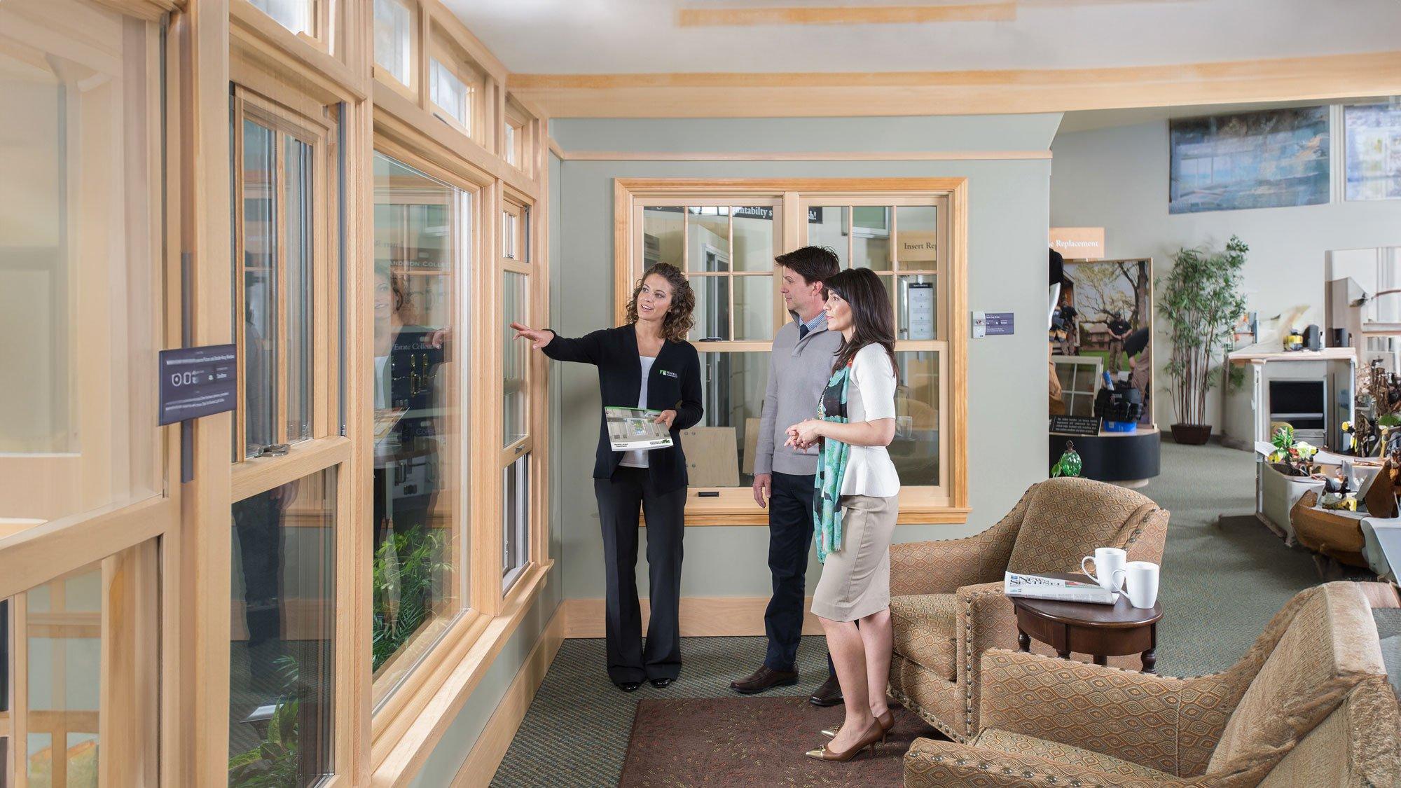 A sales person showing potential customers the window and door display in a Renewal by Andersen showroom
