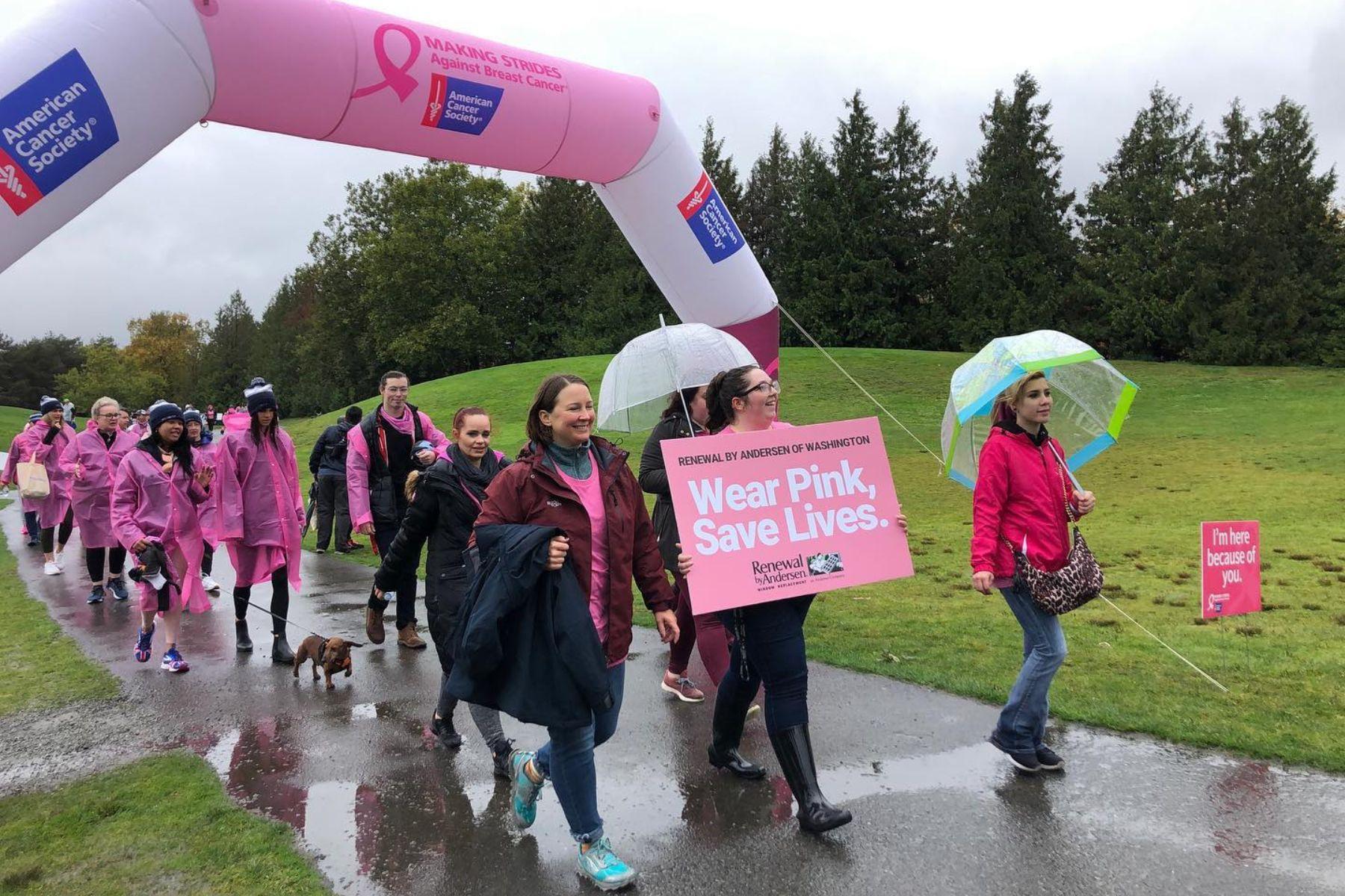 Group of RbA employees wearing pink shirts during Wear Pink, Save Lives walk in the rain. 