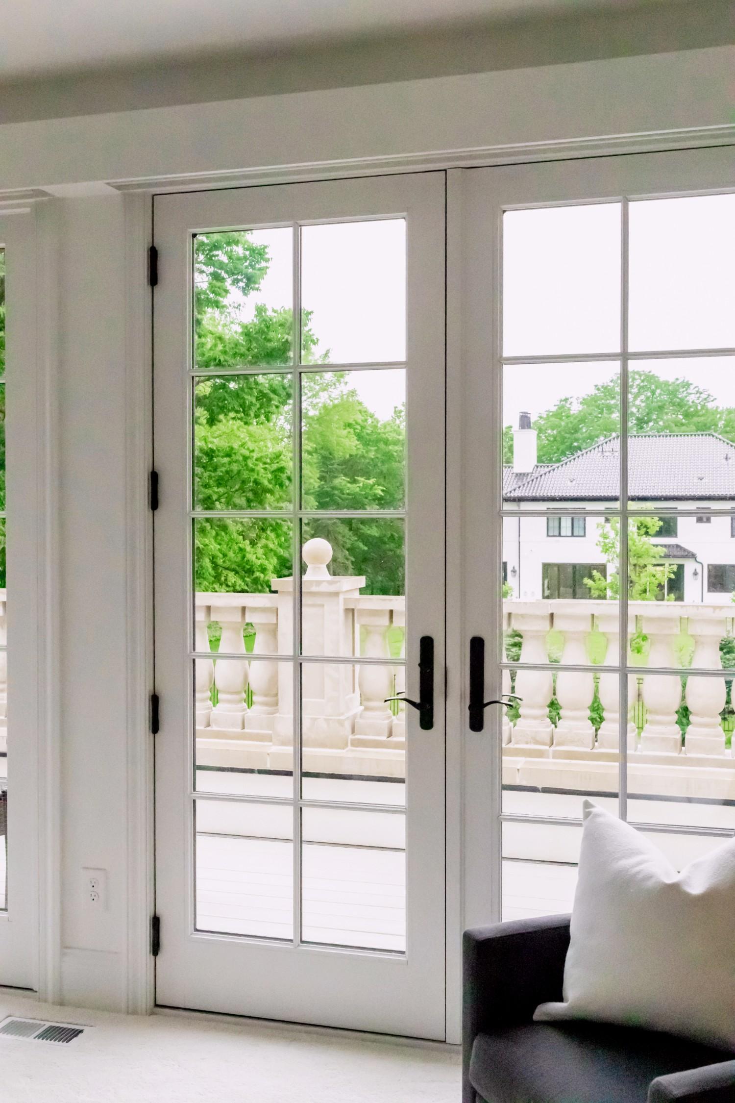 A white hinged French patio door. This is a 400 series hinged door in white with black hardware. It is a set of inswing doors.