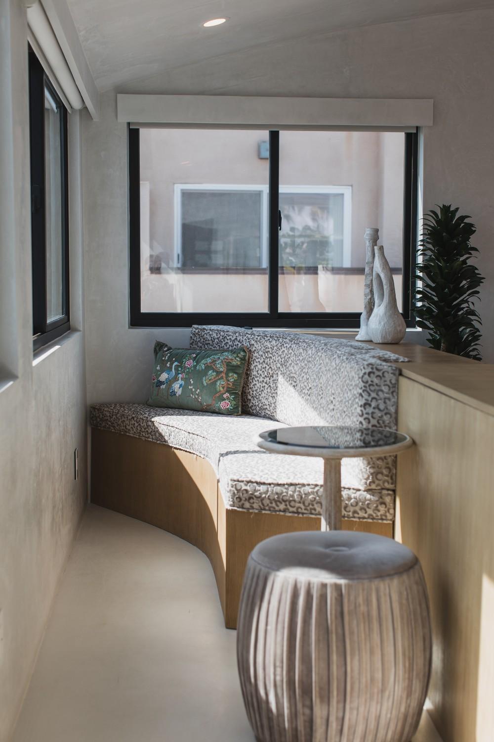 A gliding window in a cozy reading nook with a couch and some chairs.