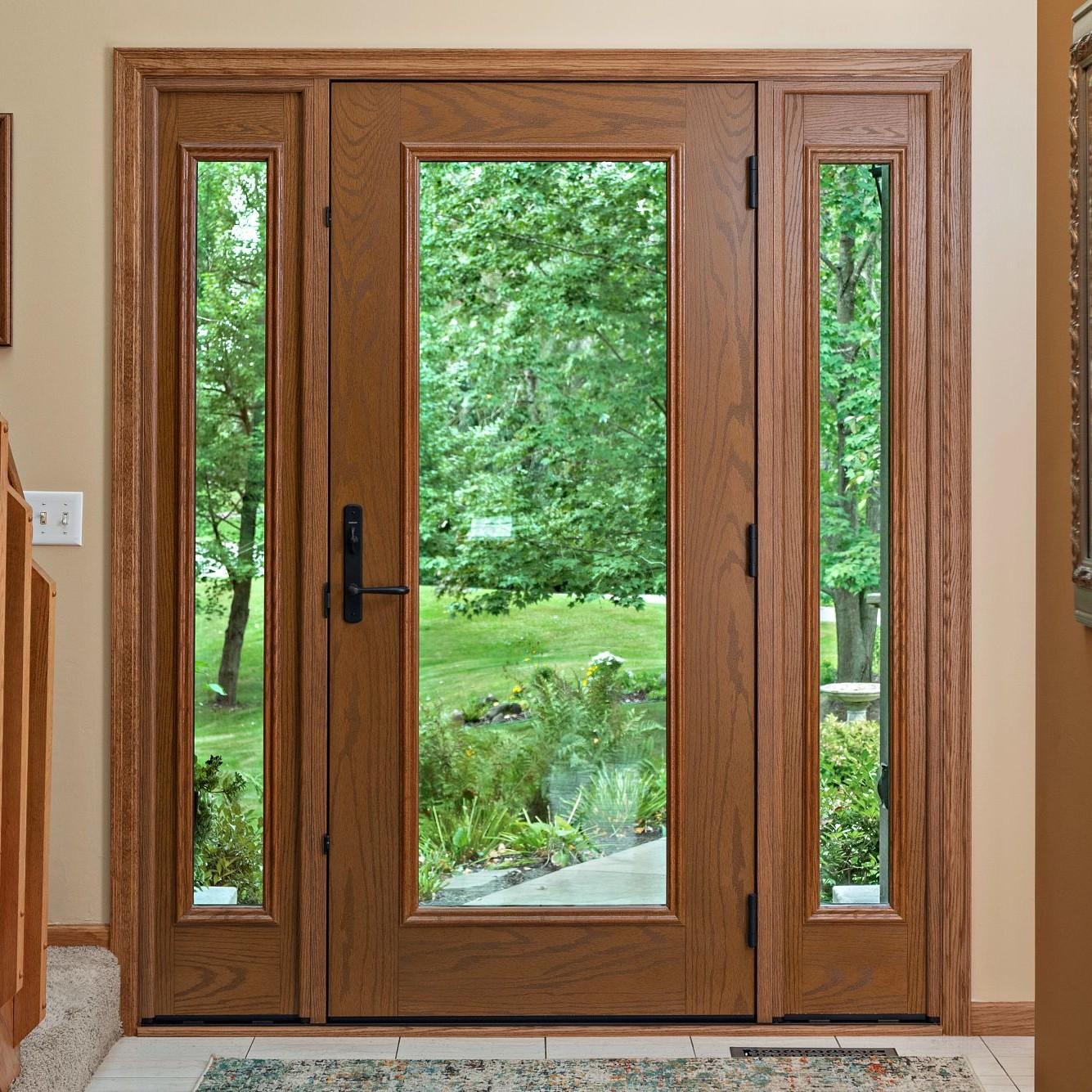 An Ensemble entry door with dual sidelights viewed from inside the home. It is full light with full glass panels. The finish is oak and the hardware is black.