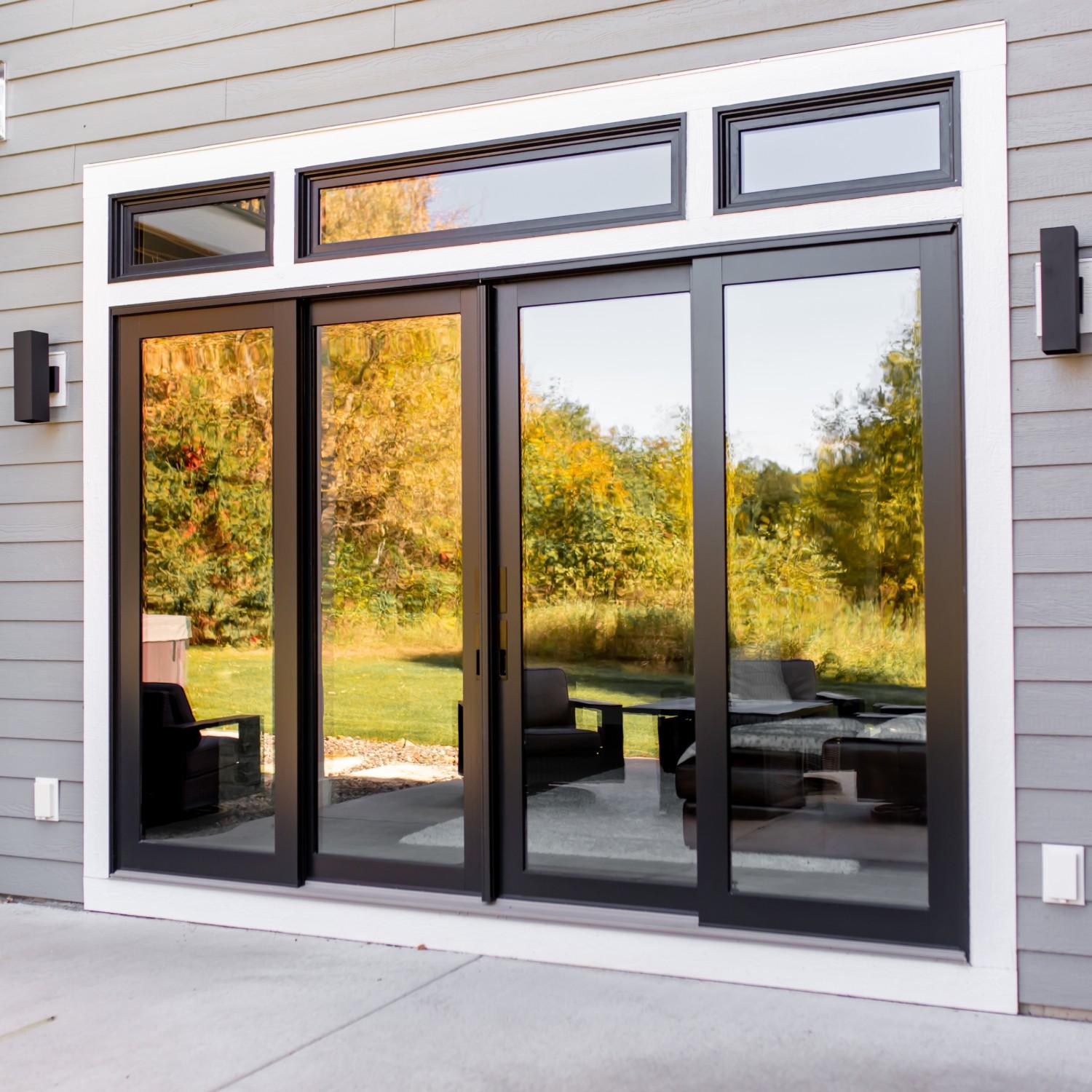 Four a-series contemporary sliding doors in black. Three transom windows above the doors add more light.