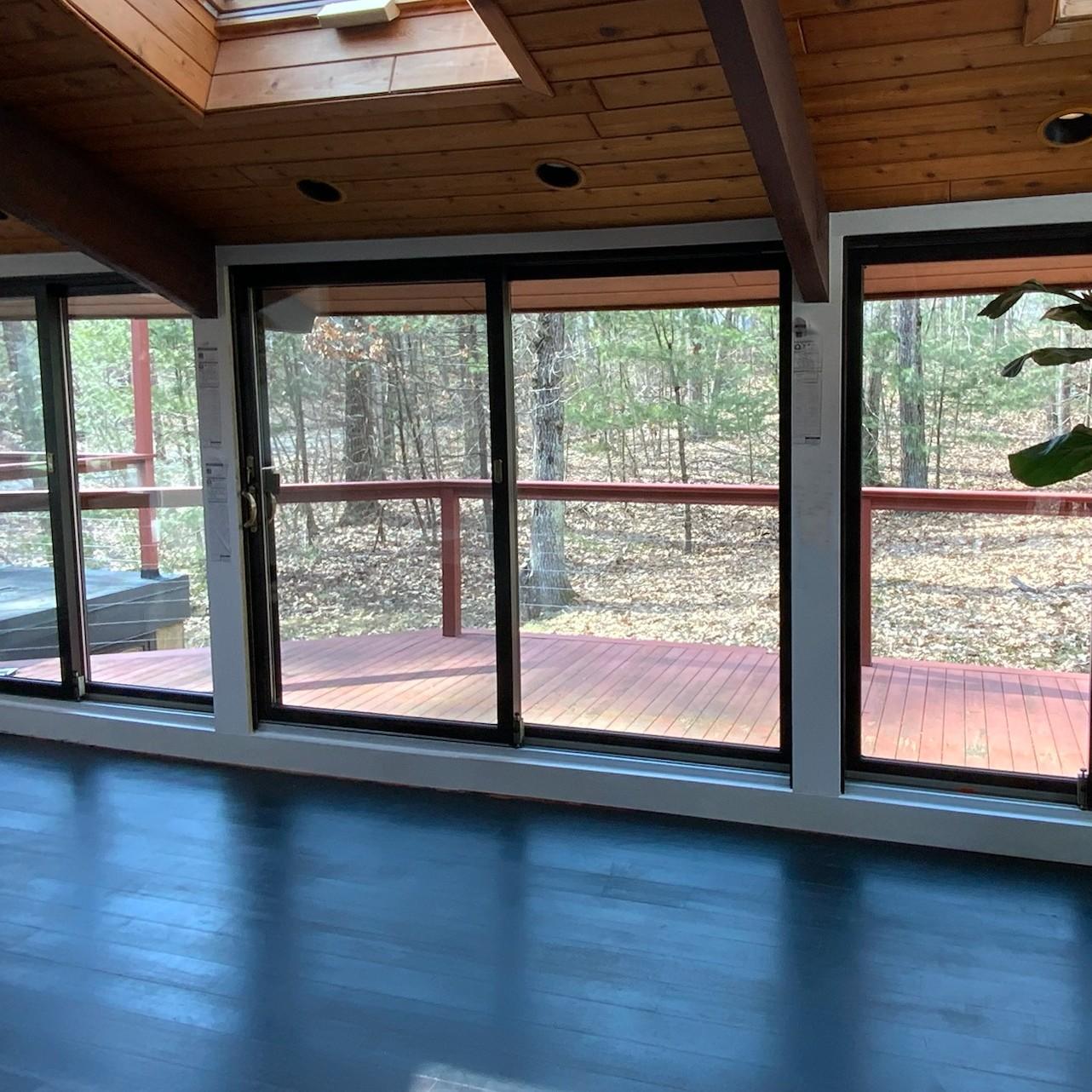 A view looking out of a solarium to the wooded yard. There are several modern style sliding glass doors to provide a lot of viewing area.