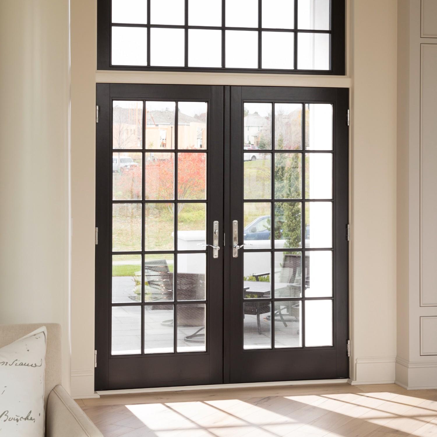 Black inswing hinged french doors with equal divided lite grilles. There is a matching picture window above.