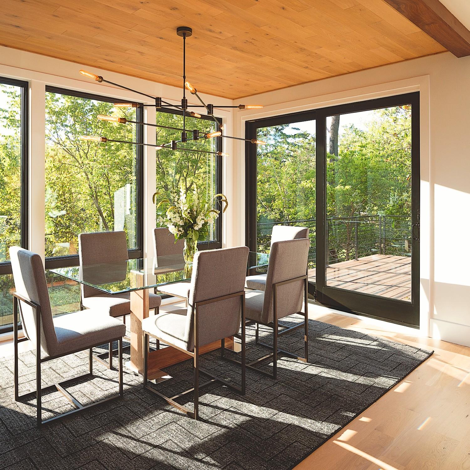 Sliding patio doors in black in a modern dining room. These doors have an auxillary footlock.