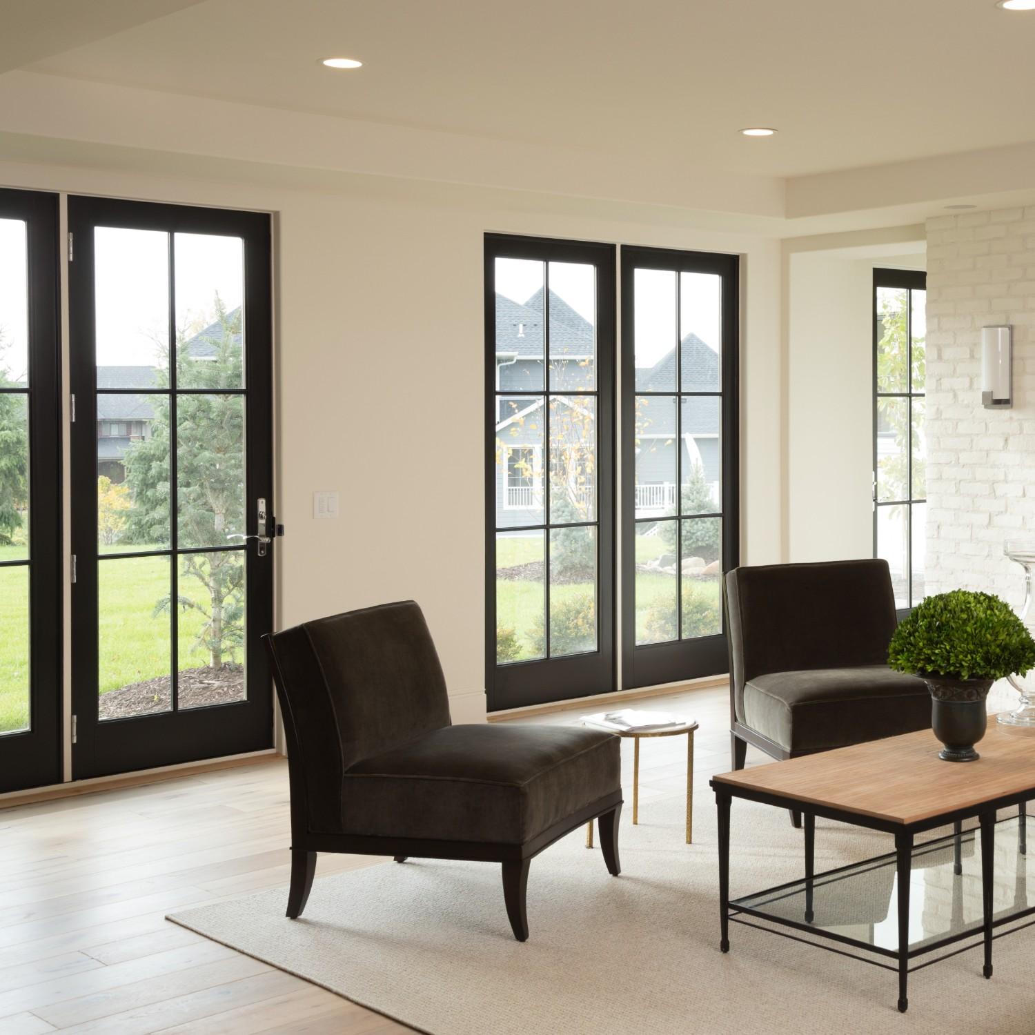 Two sets of inswing a-series patio doors. The doors are black with equal divided lite grilles.