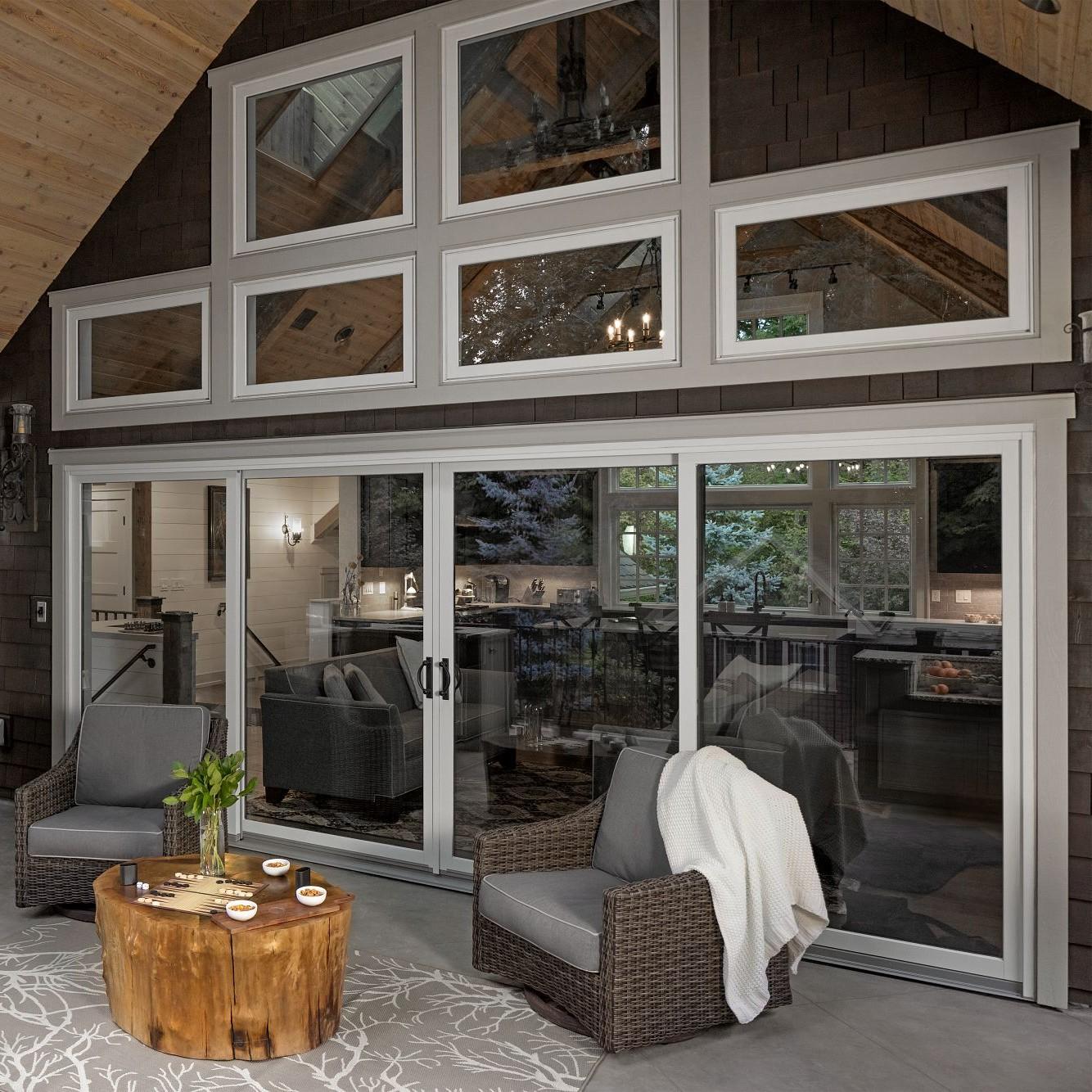 A patio with a bank of patio doors topped by rectangular picture windows.