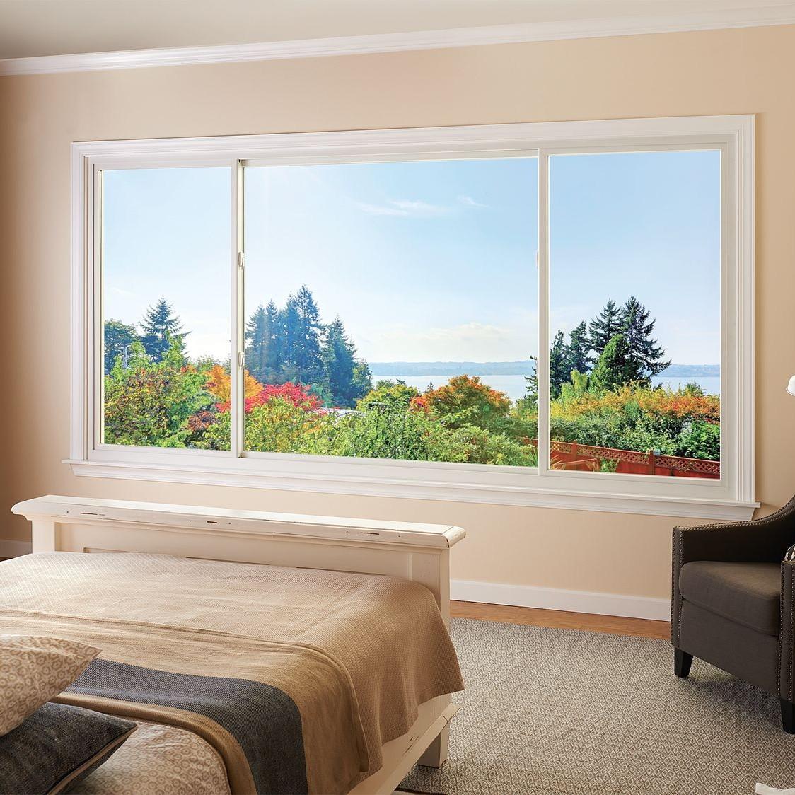 A bedroom with sliding windows looking out over the treetops to the view of the atlantic coast.