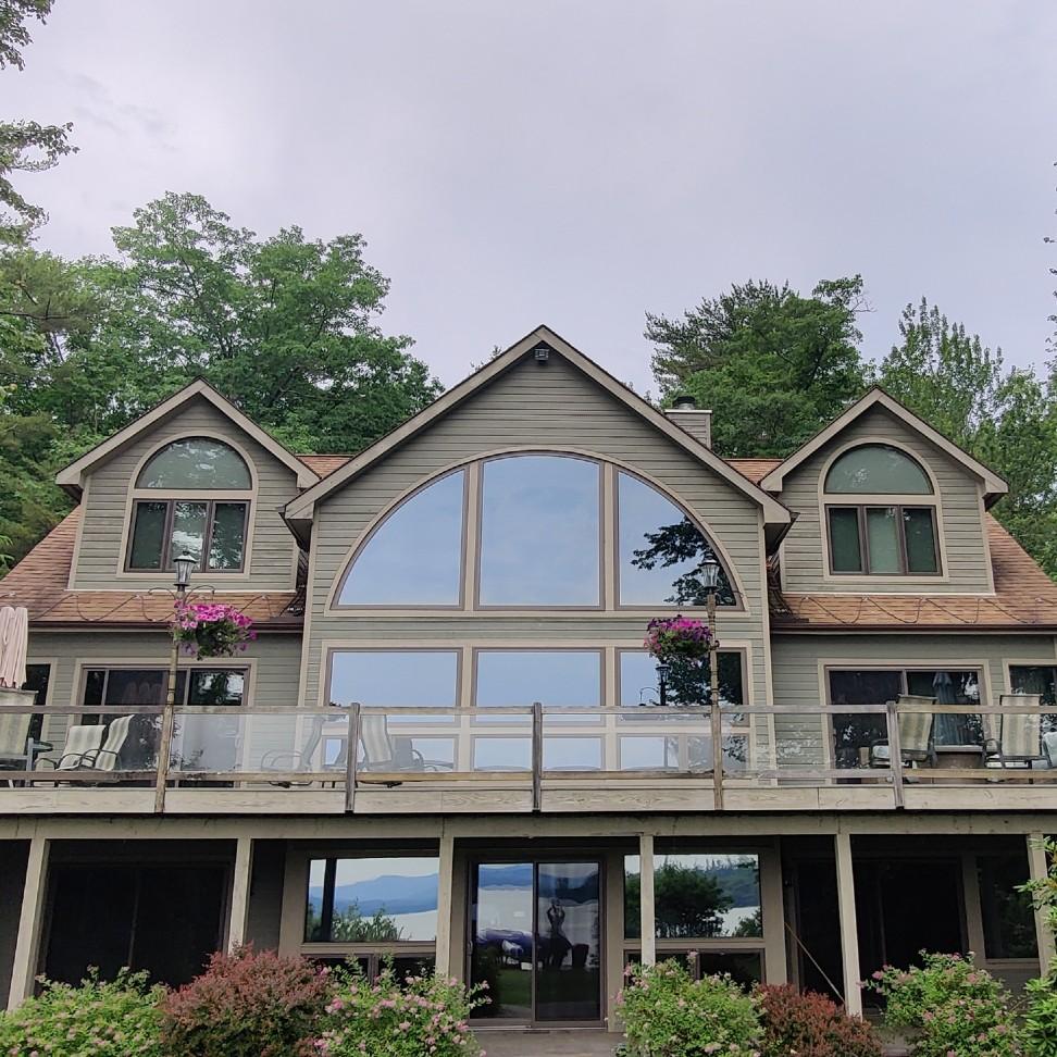 The exterior of a home, looking at the deck area. This has large specialty windows in the quarter circle shape.