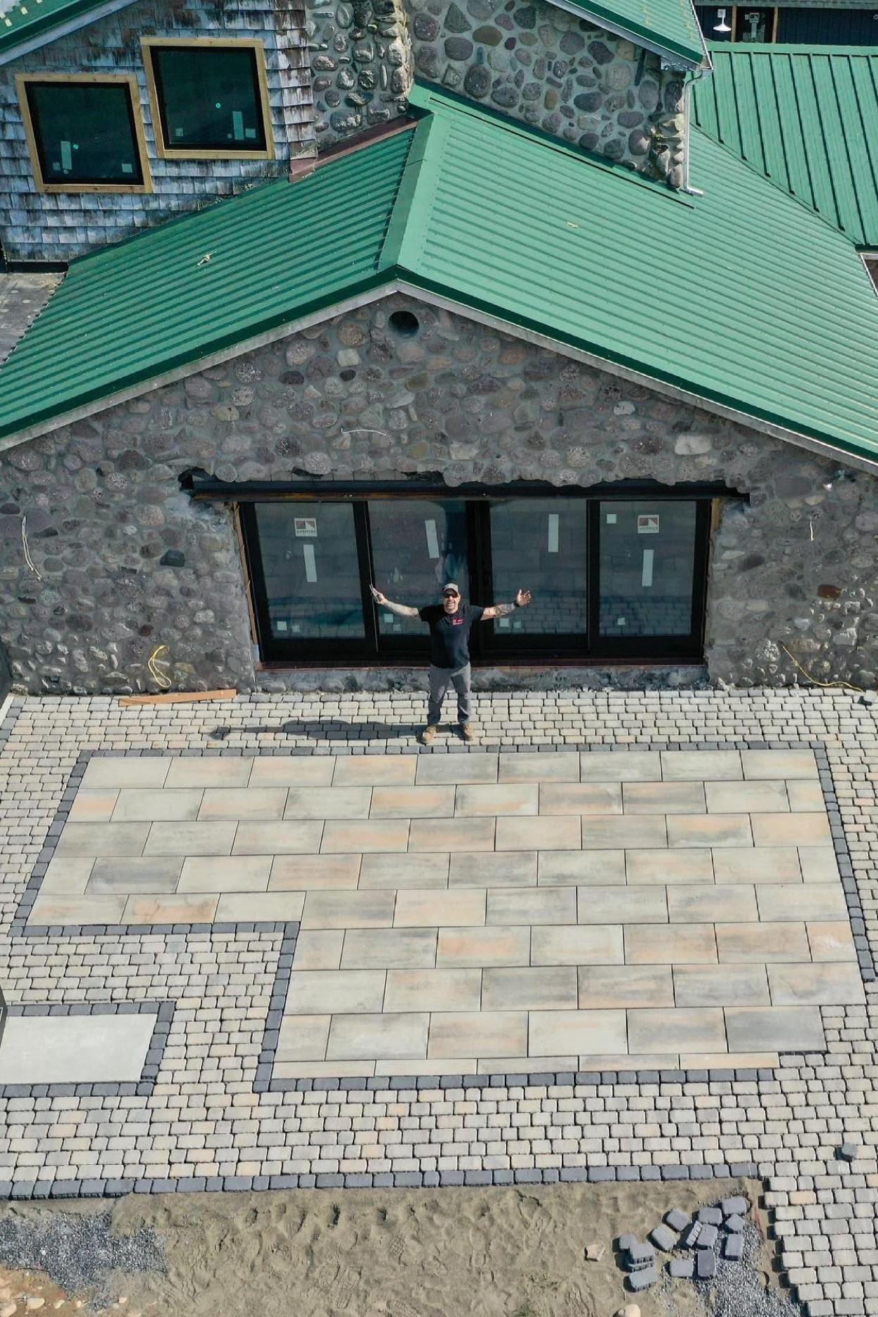 Anthony Carrino stands in front of his stone house looking jubilant.