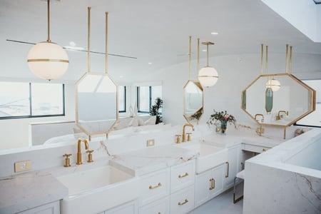 The bathroom area in the primary suite in Breegan Jane's california beach house. It is all white with gold fixtures.